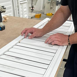 A craftsman hand-building a quality plantation shutter panel on the workbench