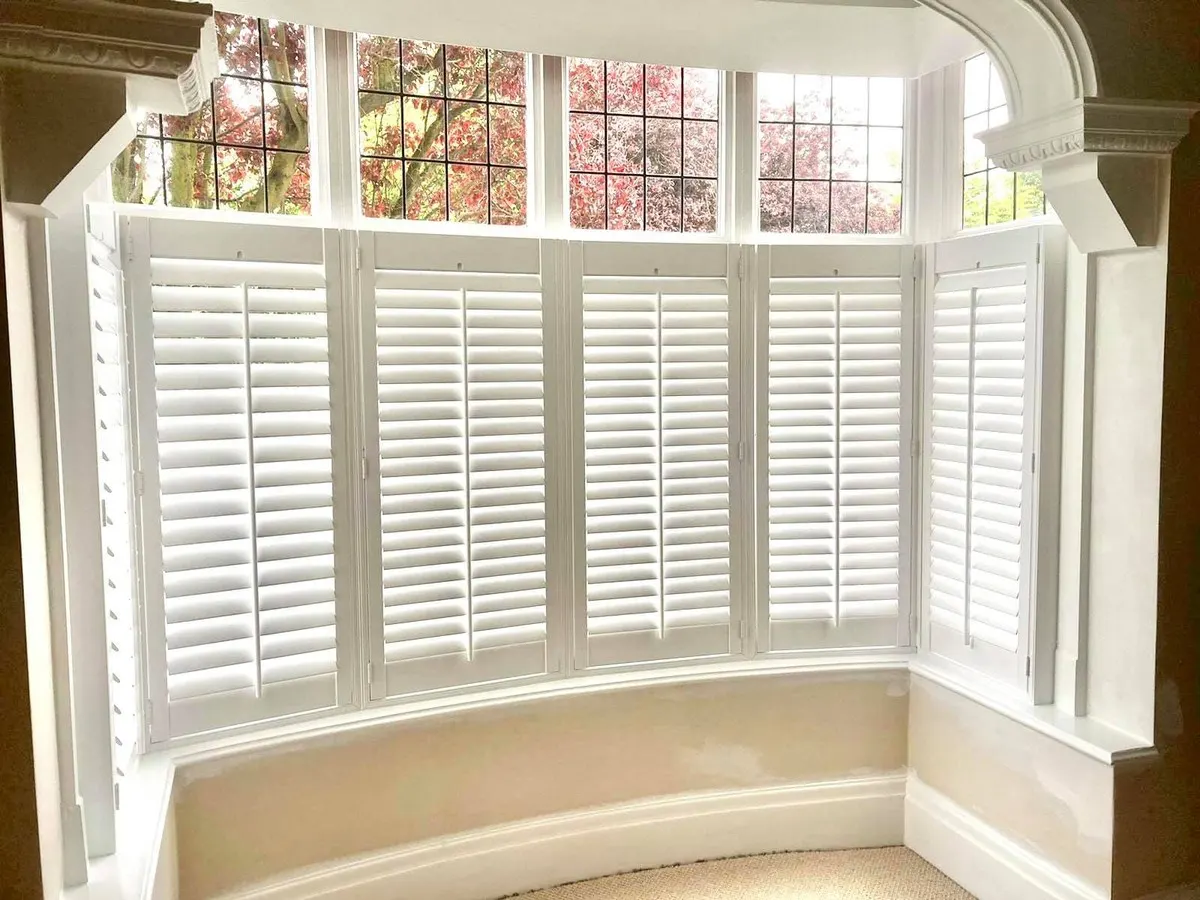 Café-style plantation shutters in a curved bow window with a curved window seat below