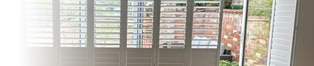 Bi-fold door shutters on a tracked system, closed across a wide opening