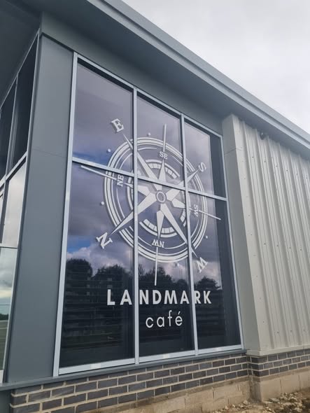 Landmark Café exterior with shutters and compass logo window graphic