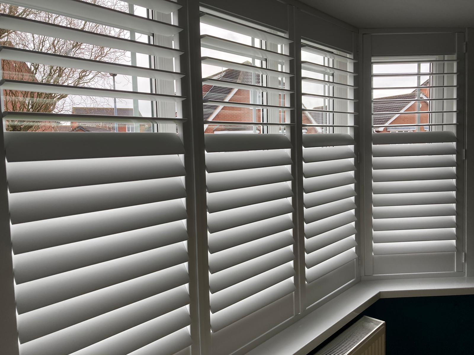 White shutters on a window in a room.