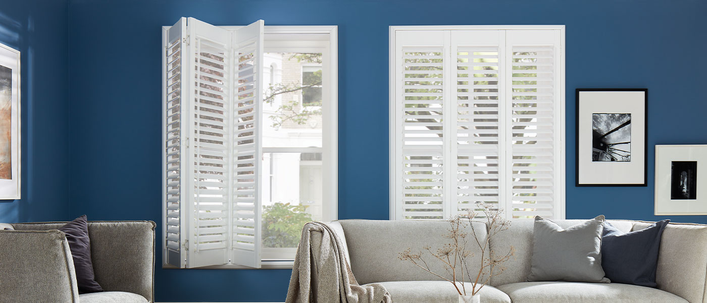 A living room with blue walls and white shutters.