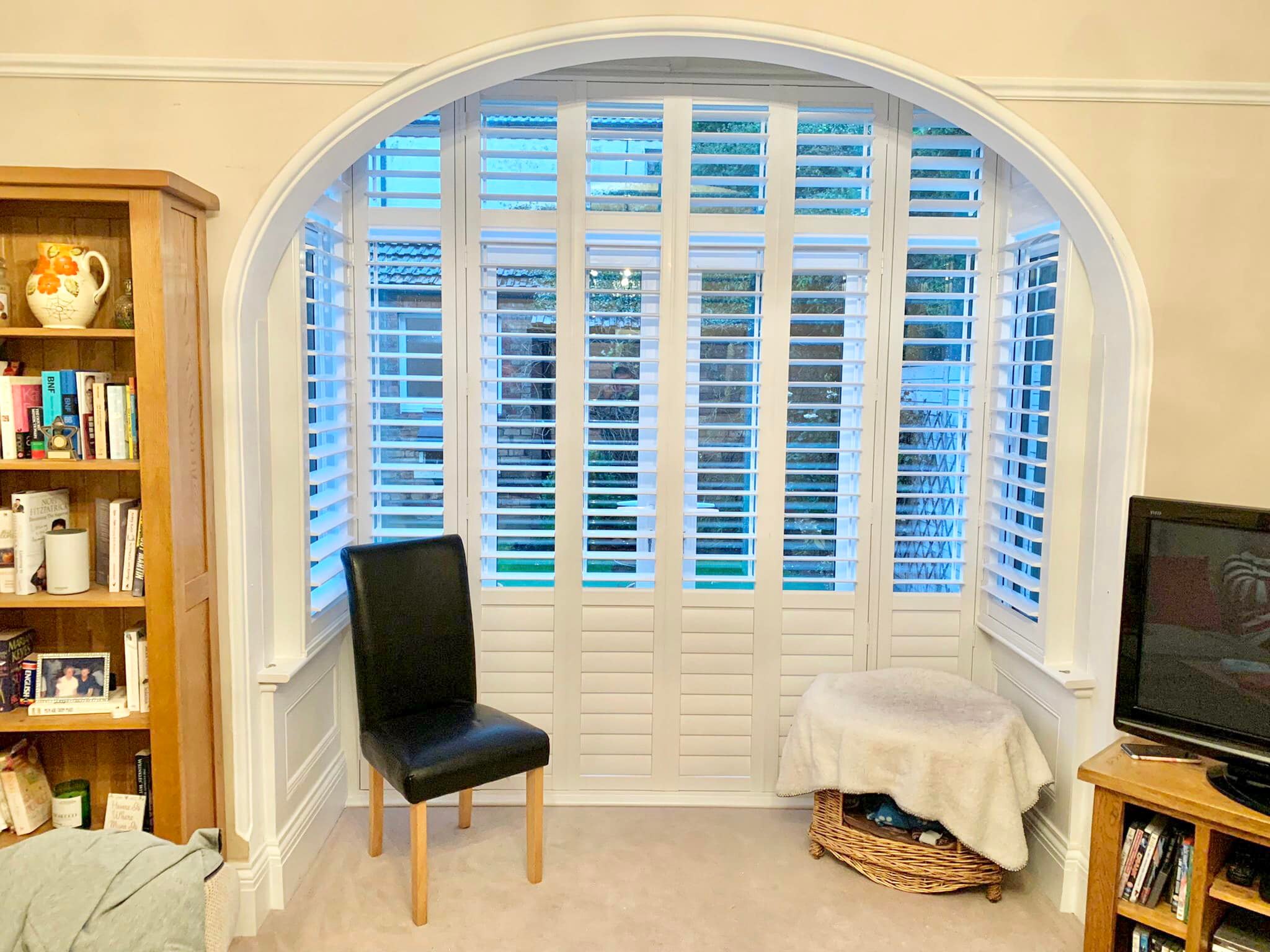 A living room with arched window shutters.