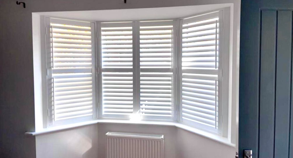 White shutters on a window in a room.
