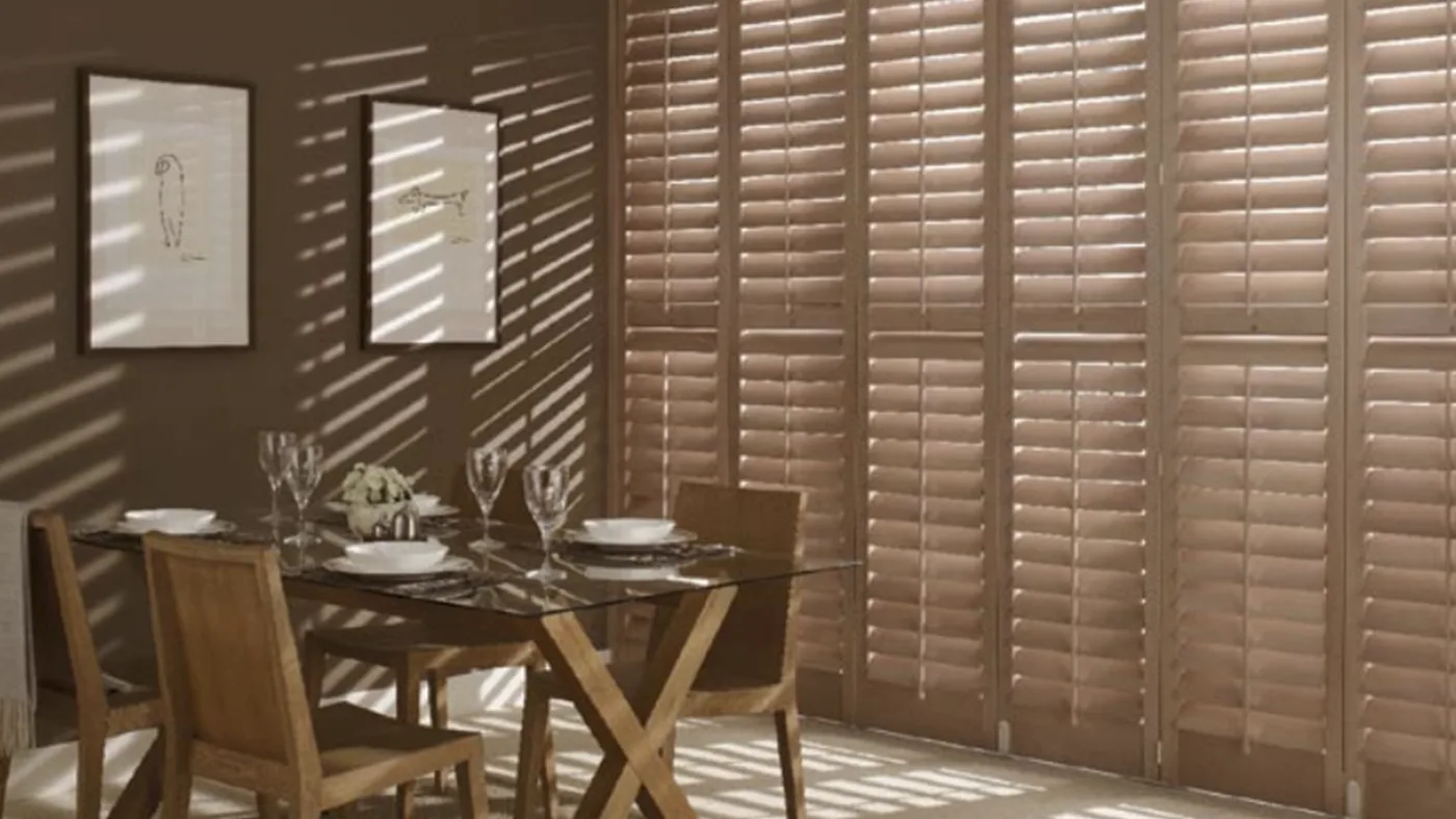 A dining room with brown shutters and a table.