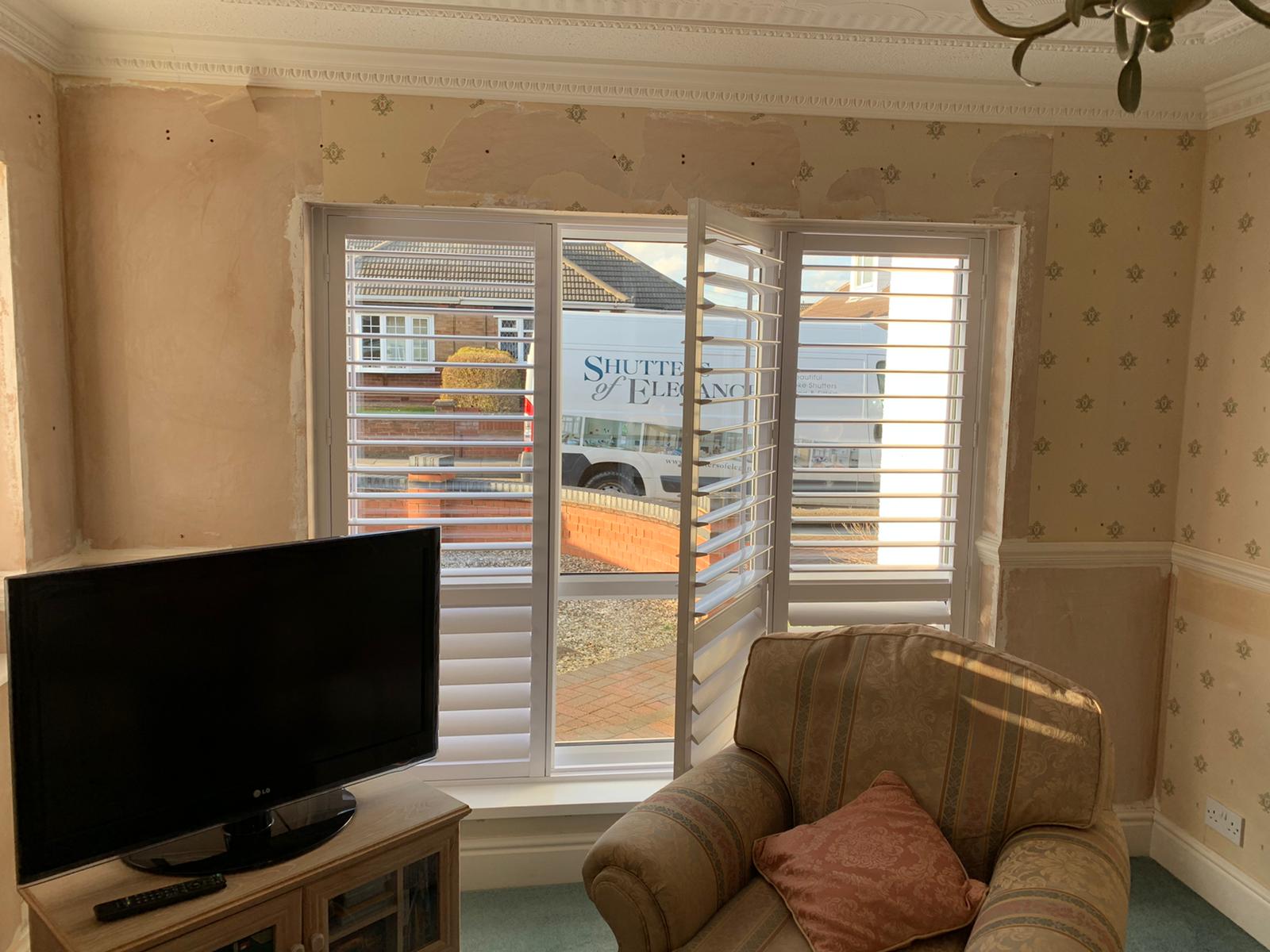 A living room with shutters and a tv.
