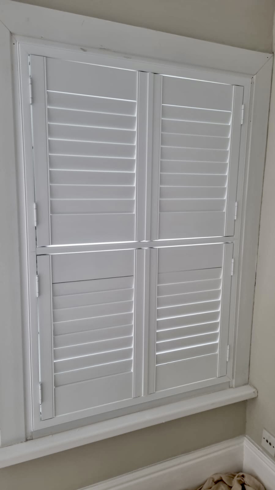 White shutters on a window in a room.