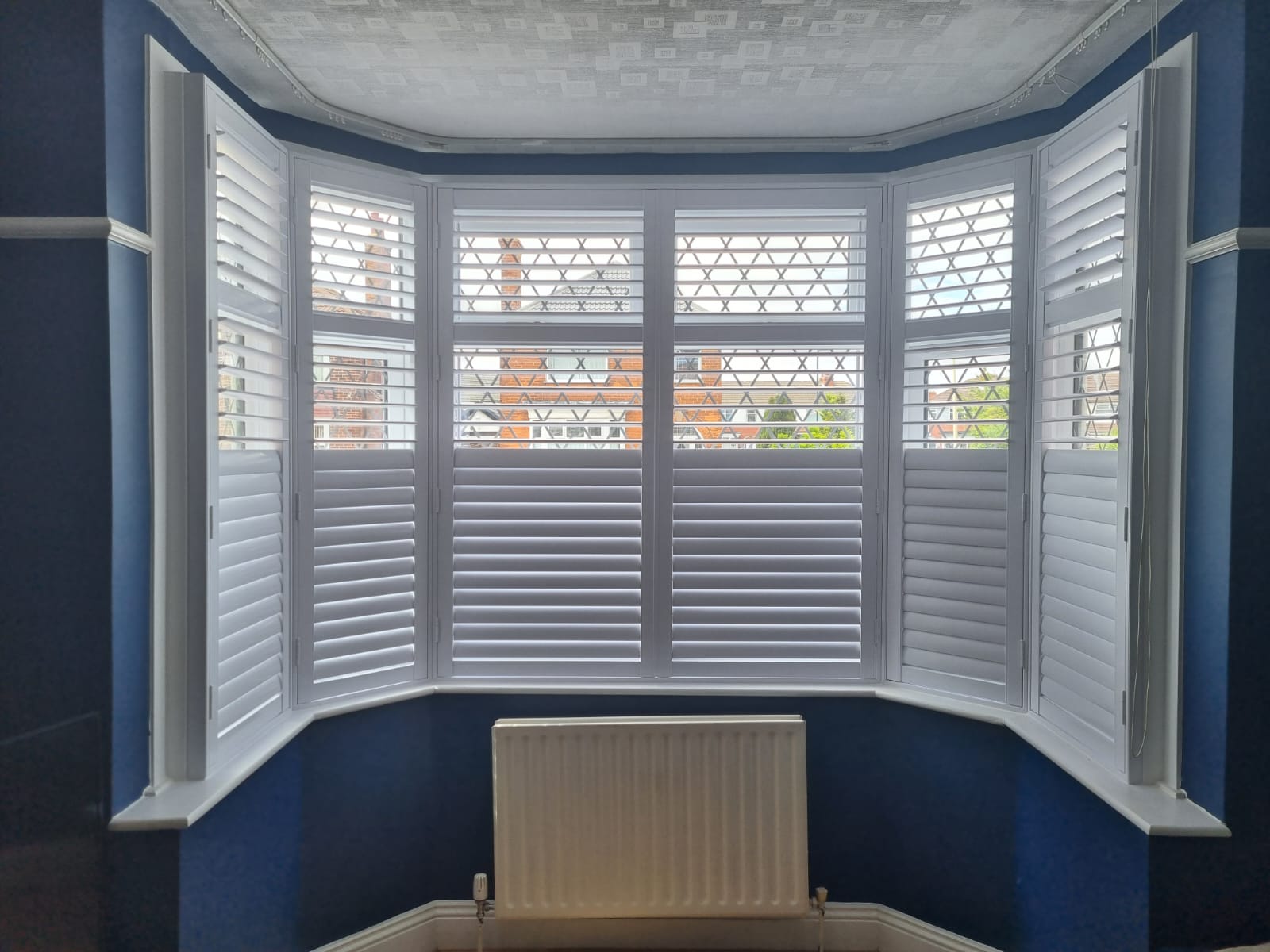 A room with white shutters and a radiator.