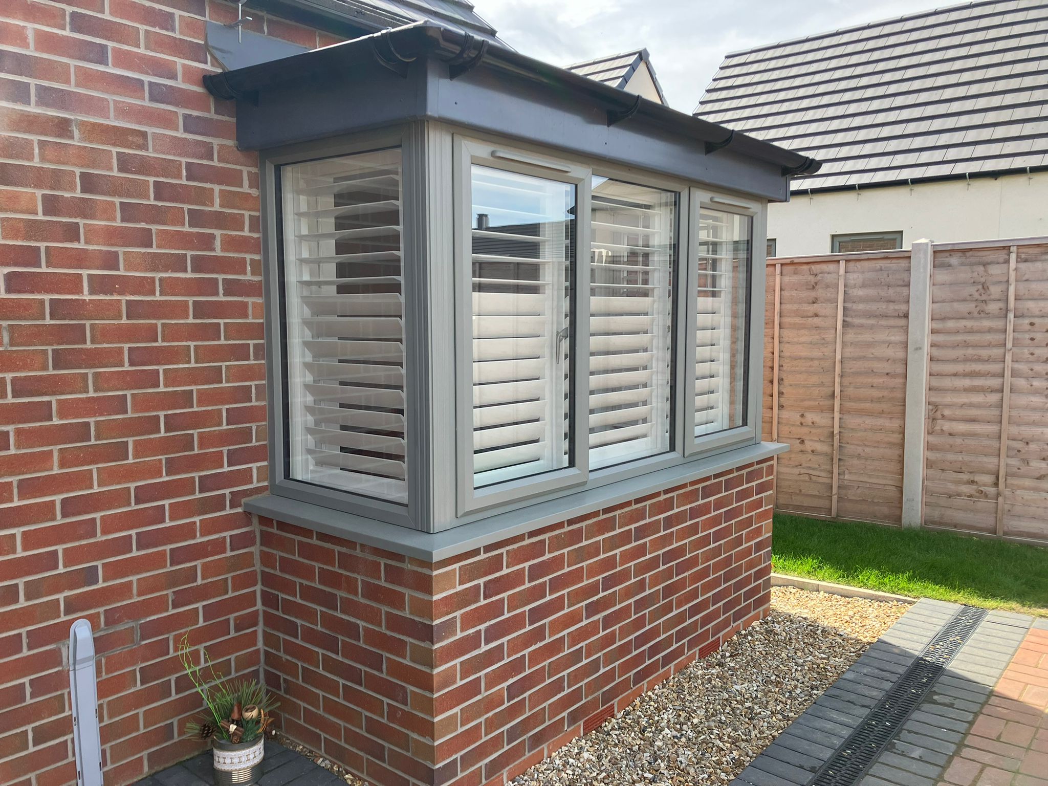 A window with shutters on the side of a brick house.
