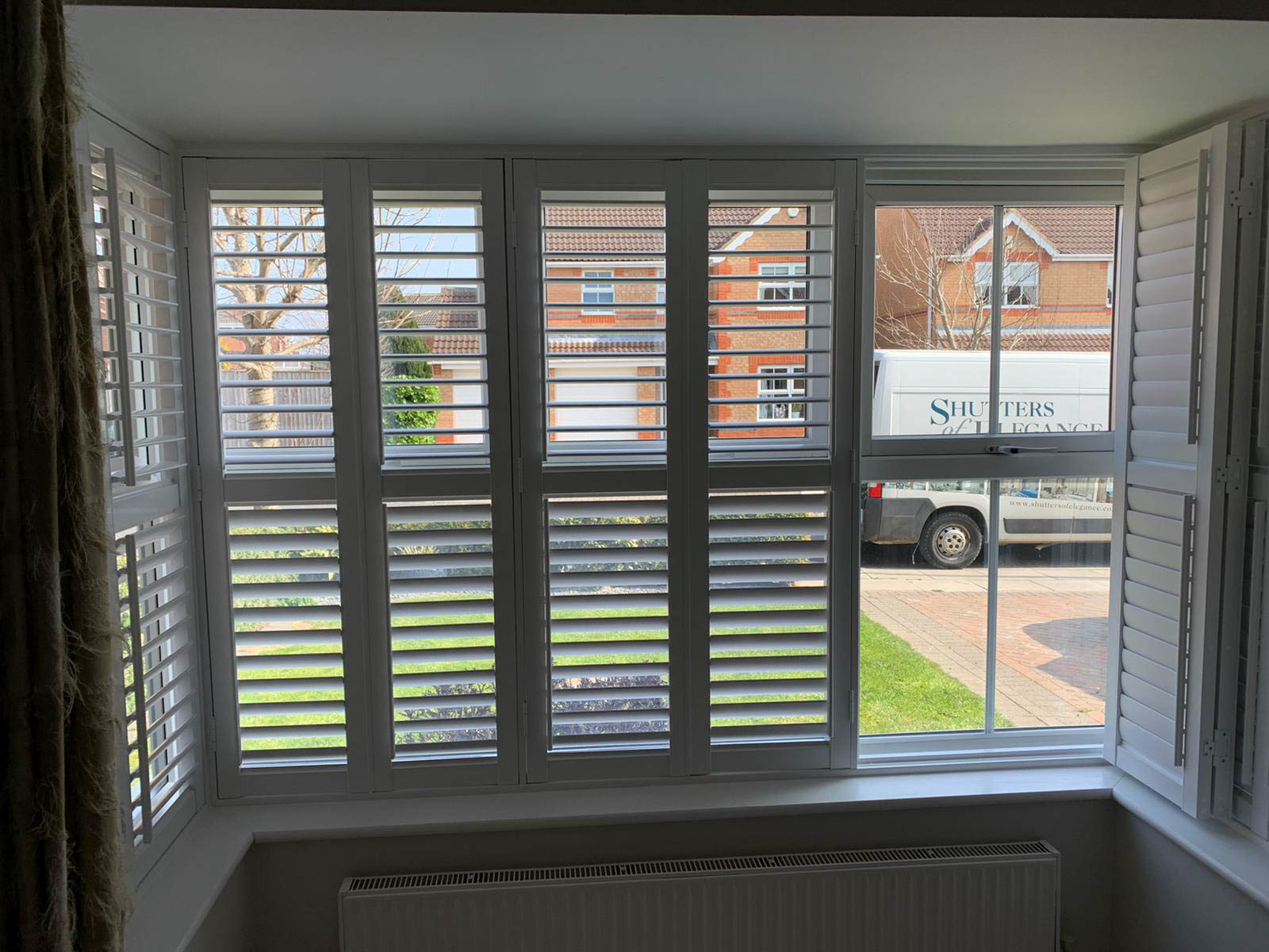 White shutters on a window in a room.