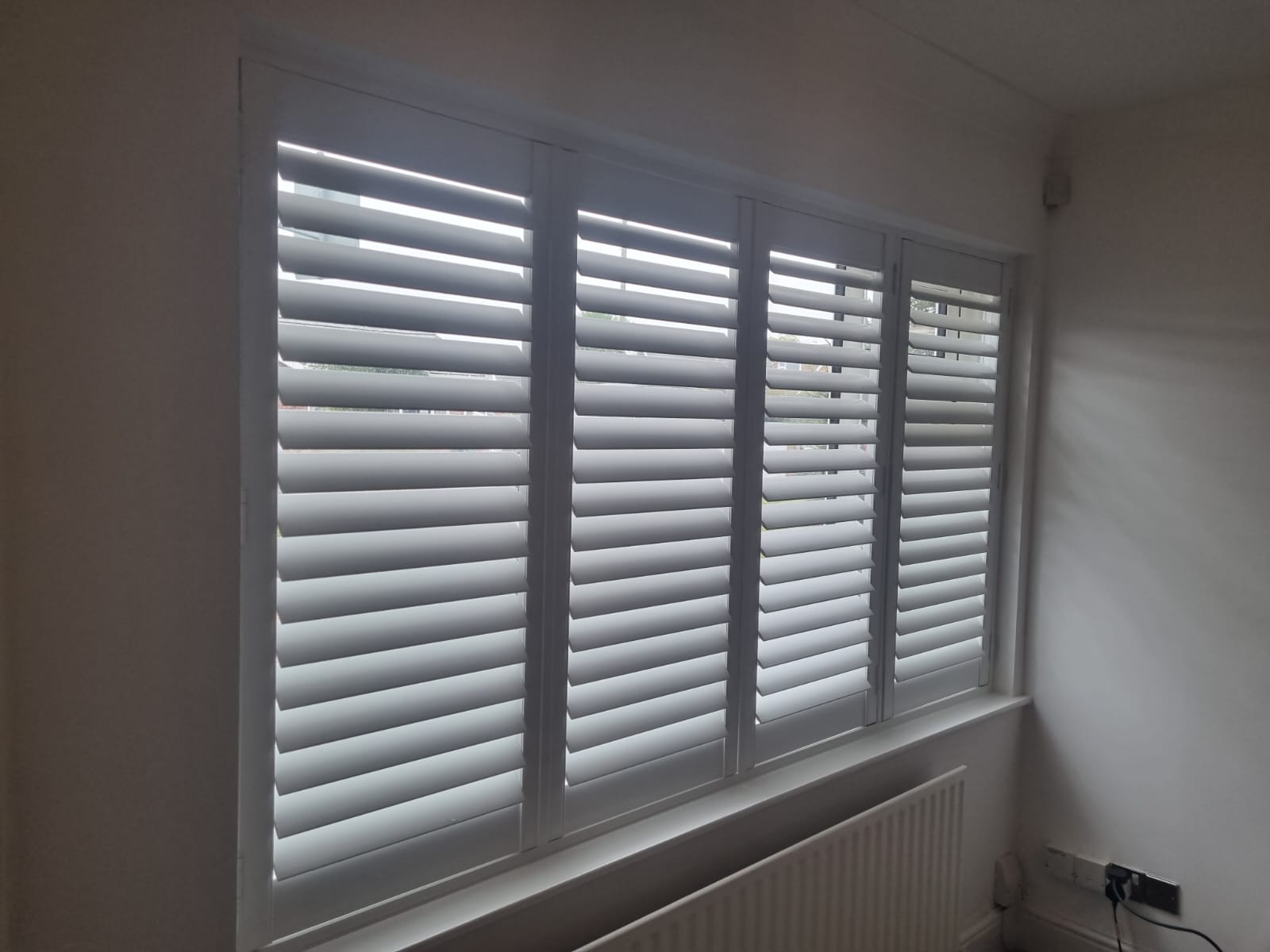 White shutters on a window in a room.