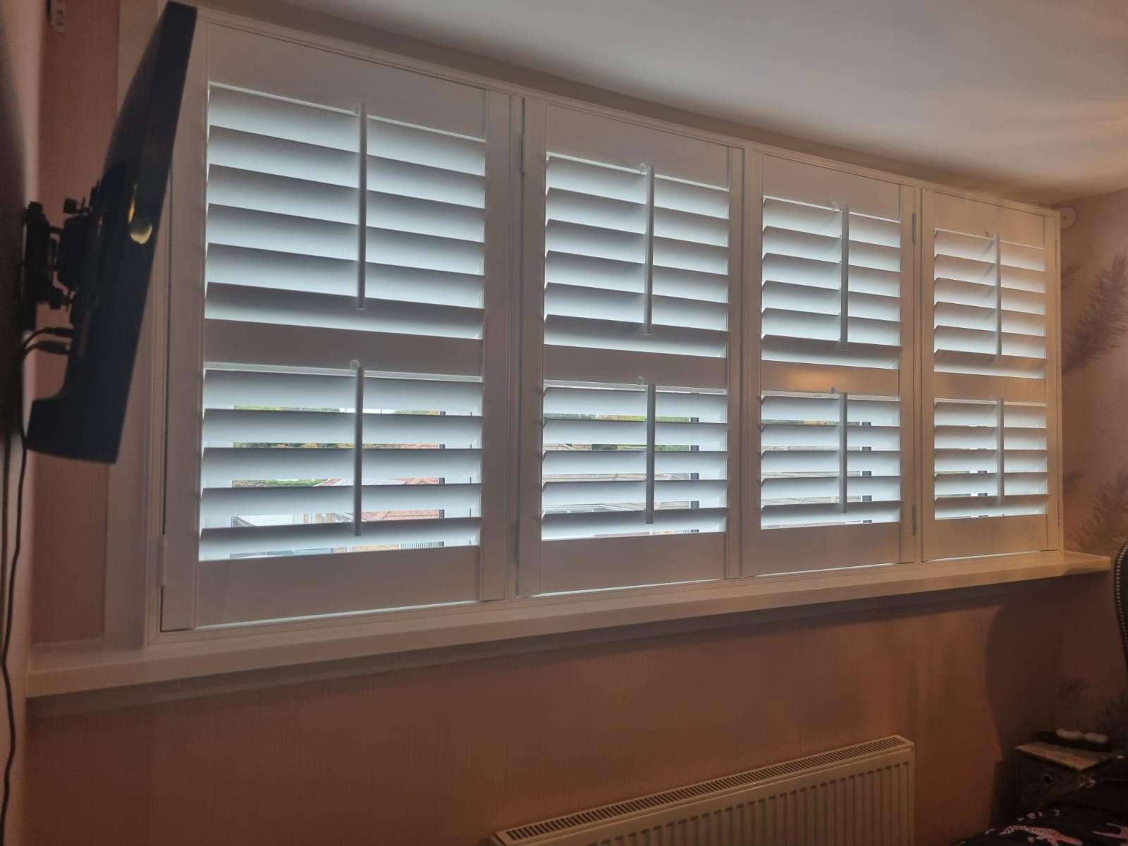 White shutters on a window in a bedroom.