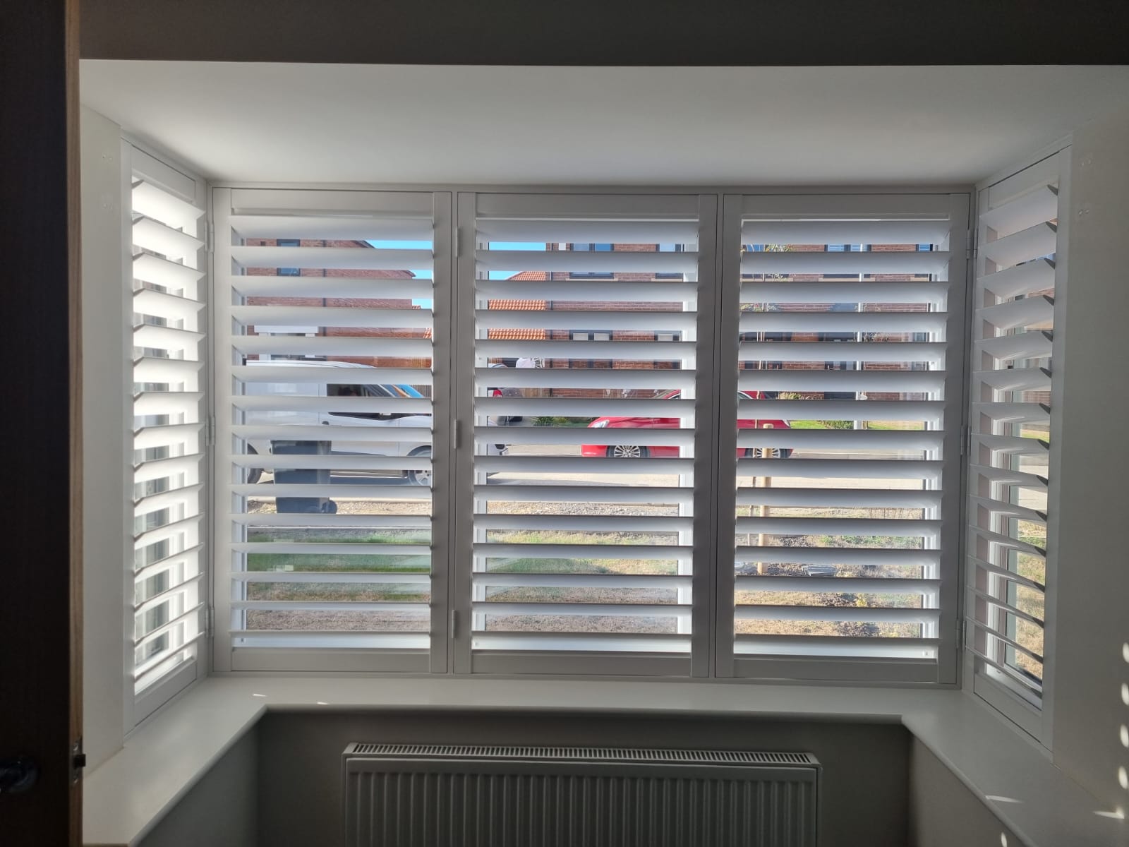 White shutters on a window in a room.