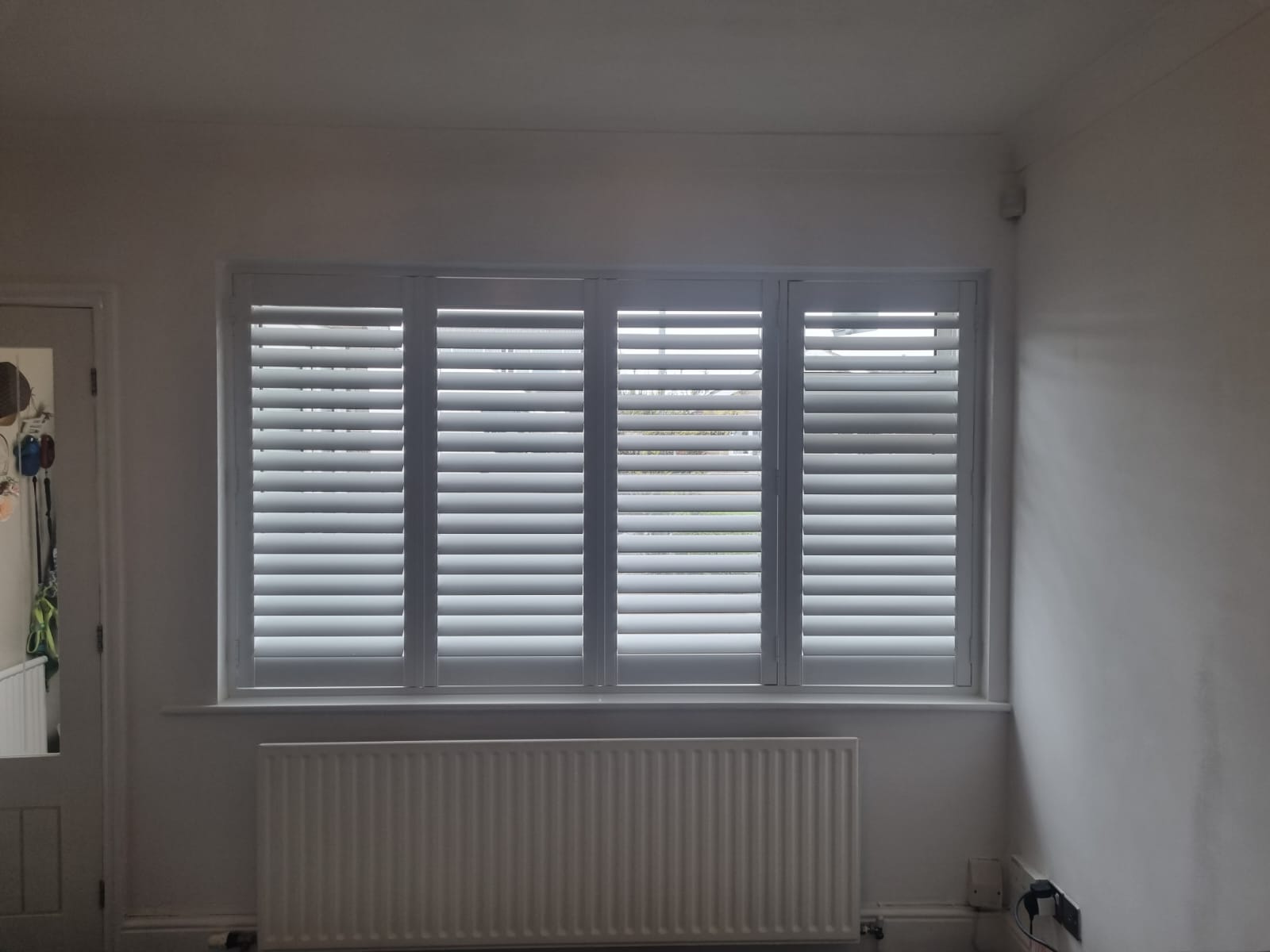 A room with white shutters and a radiator.