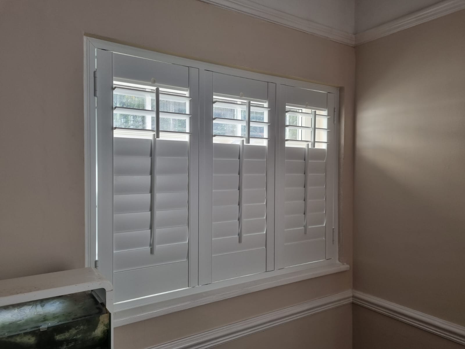 White shutters on a window in a room.