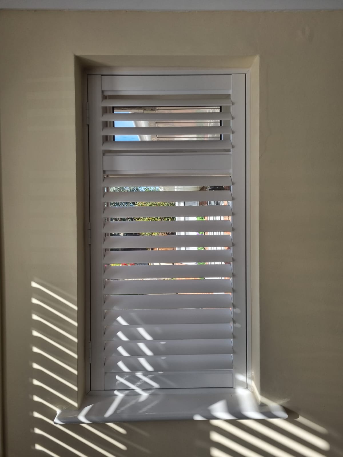 White shutters on a window in a room.