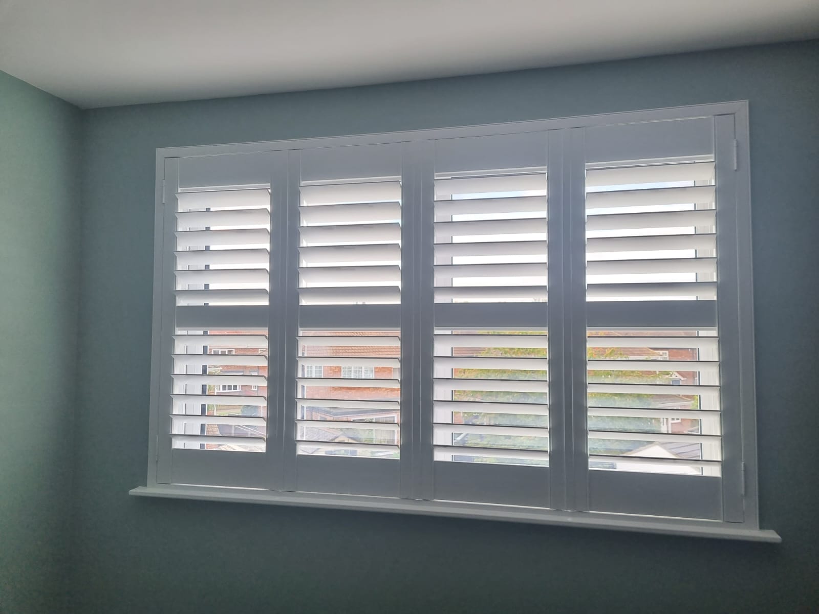 White shutters on a window in a room.