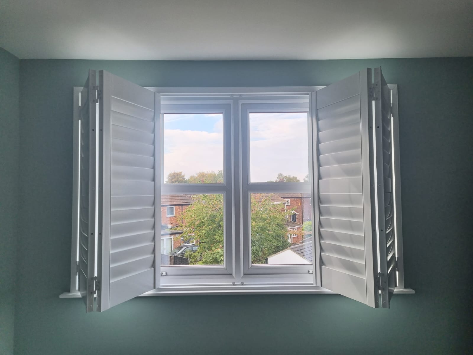 White shutters on a window in a room.