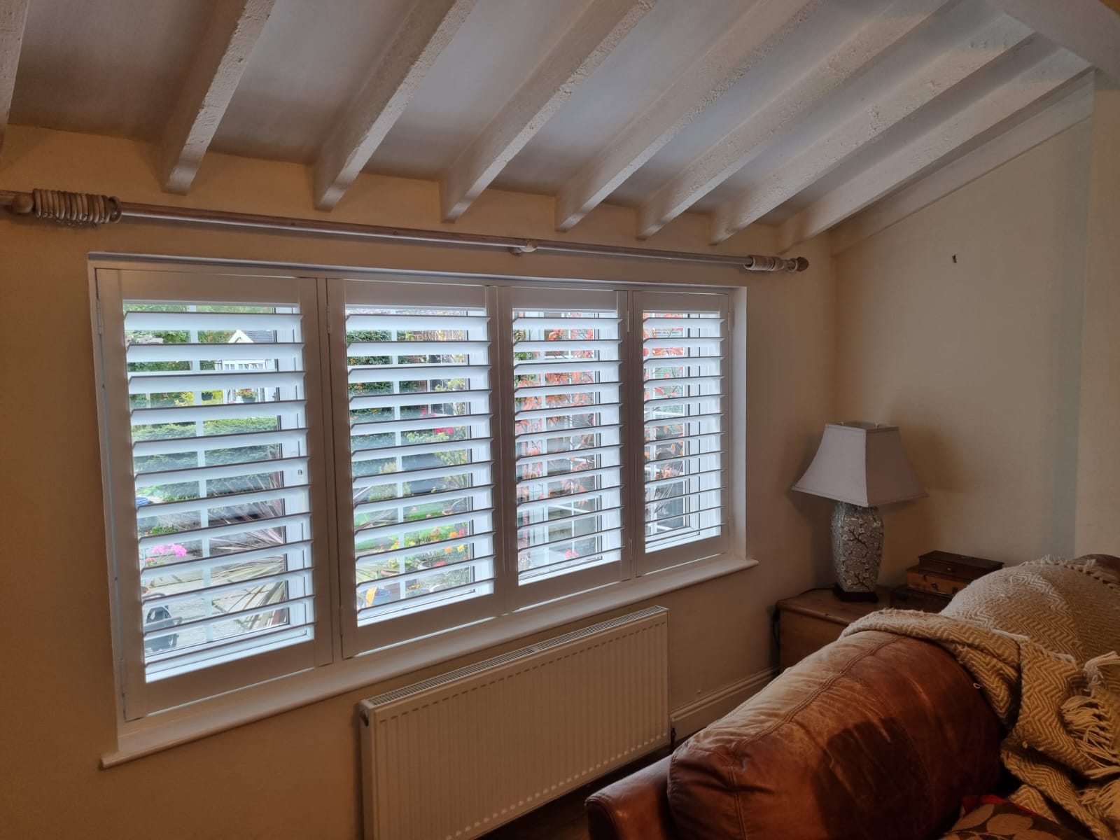 A living room with white shutters on the windows.