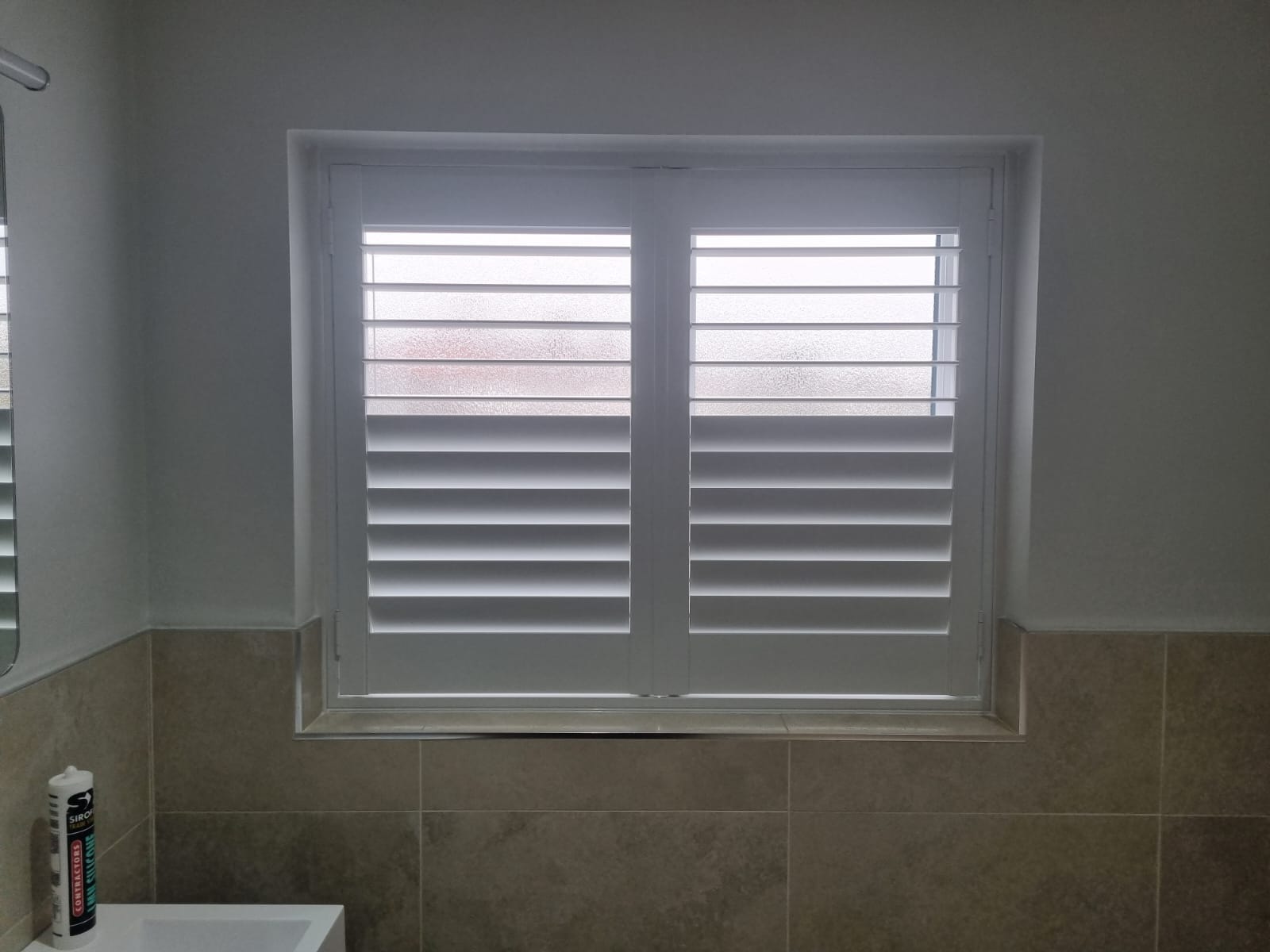 A bathroom with white shutters and a sink.