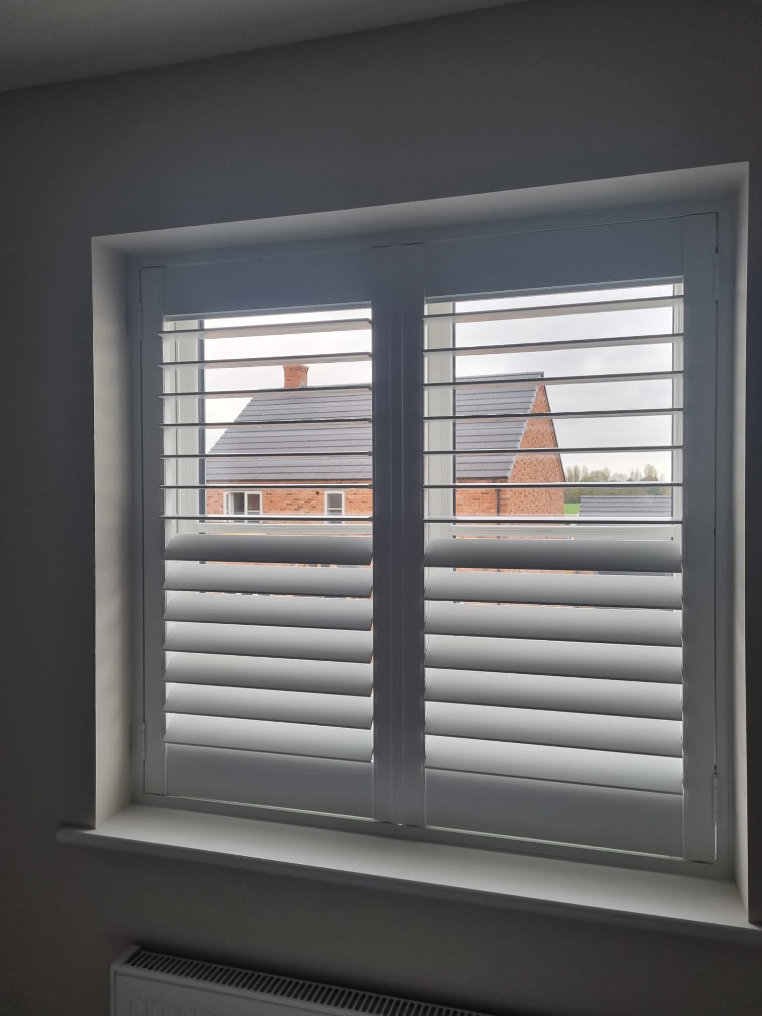 White shutters on a window in a room.
