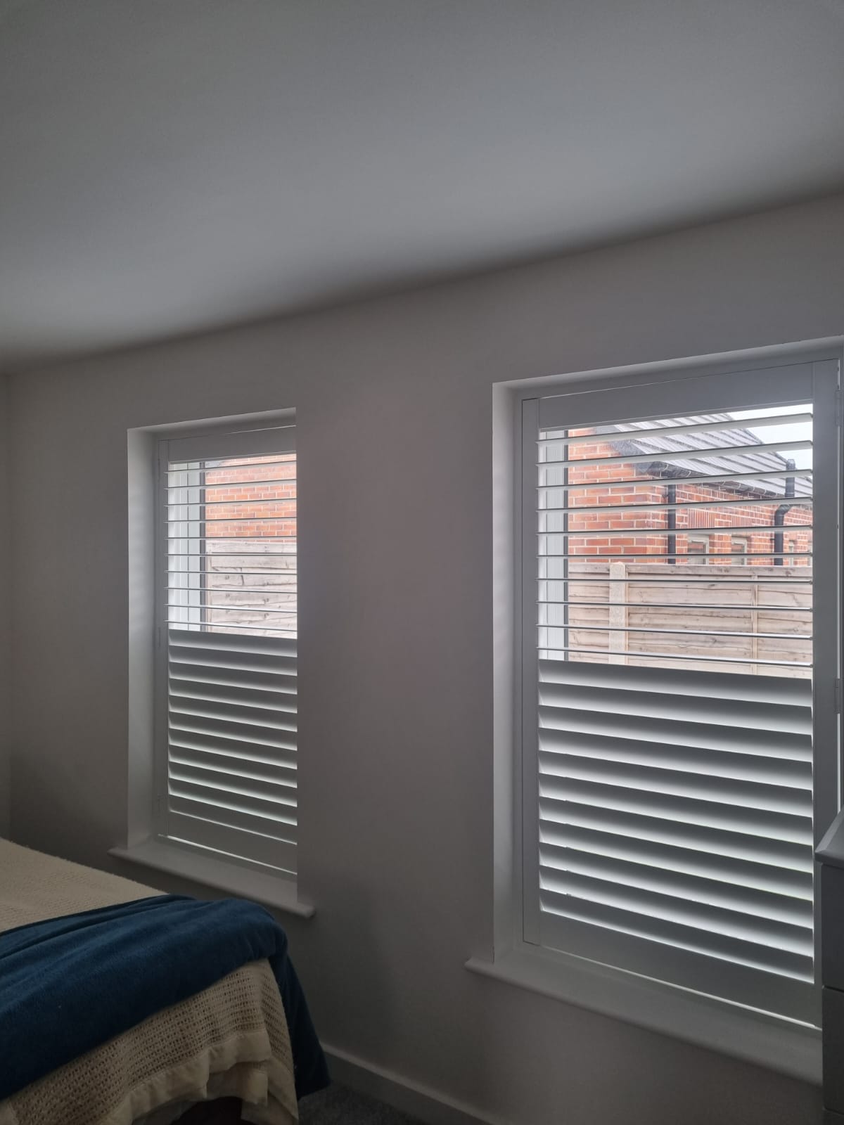A bedroom with white shutters and a bed.