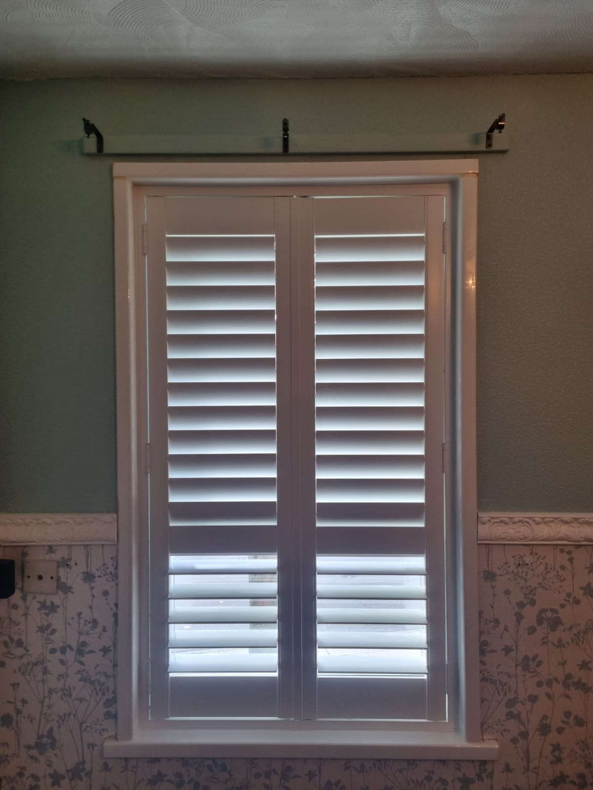 White shutters on a window in a bathroom.