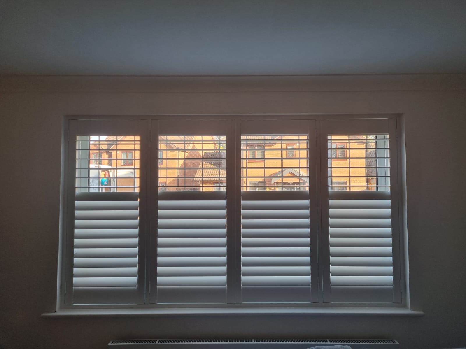 White shutters on a window in a room.