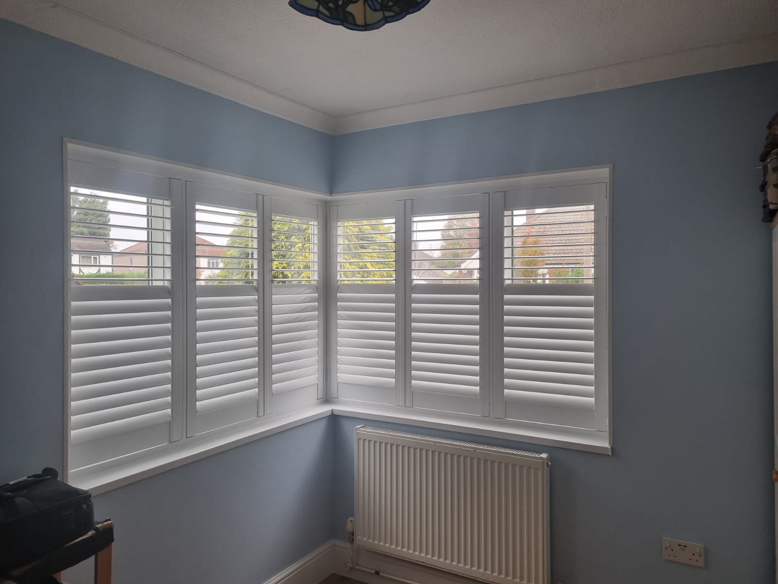 A room with white shutters and a radiator.