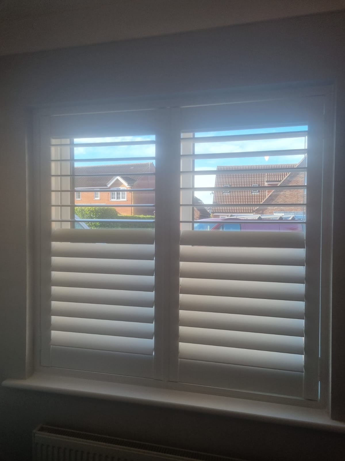 White shutters on a window in a room.