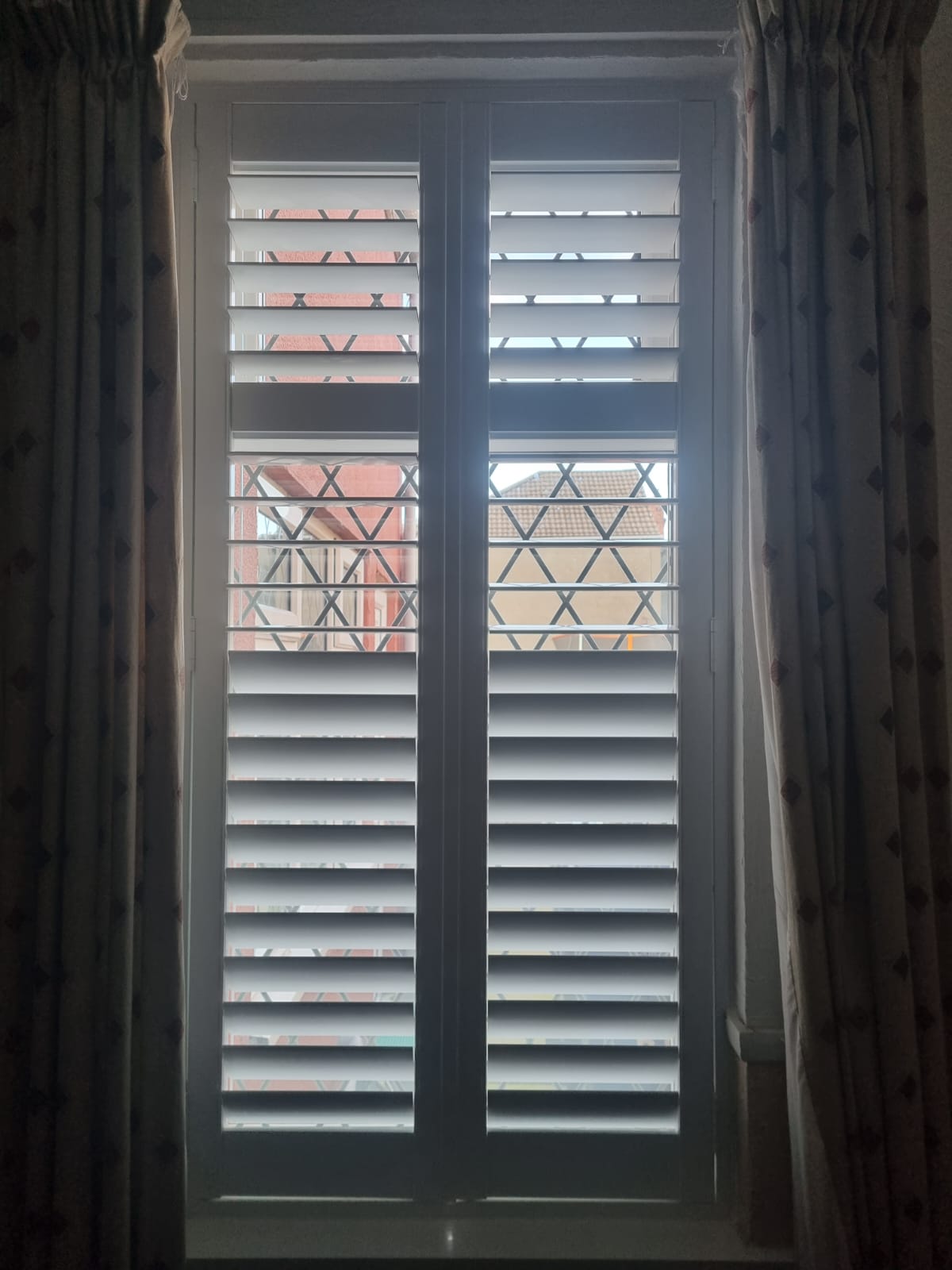 White shutters on a window in a room.