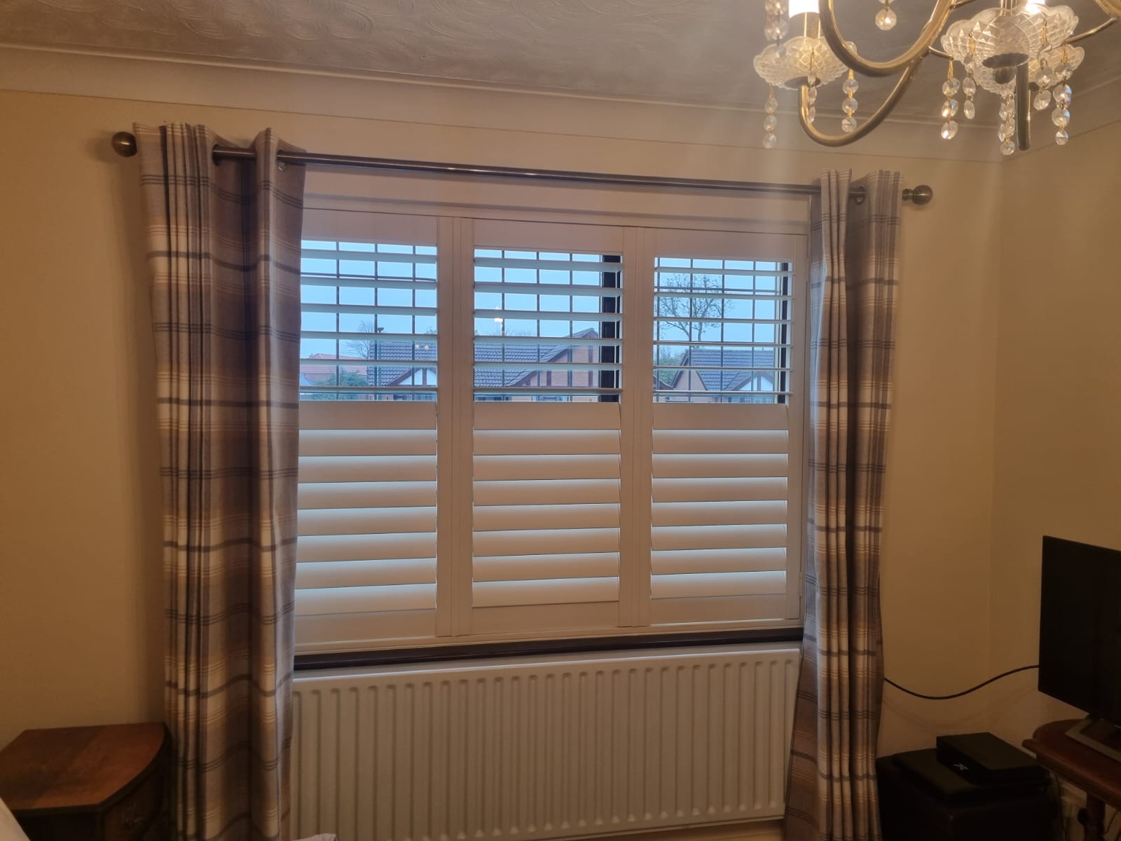 A room with white shutters and a radiator.