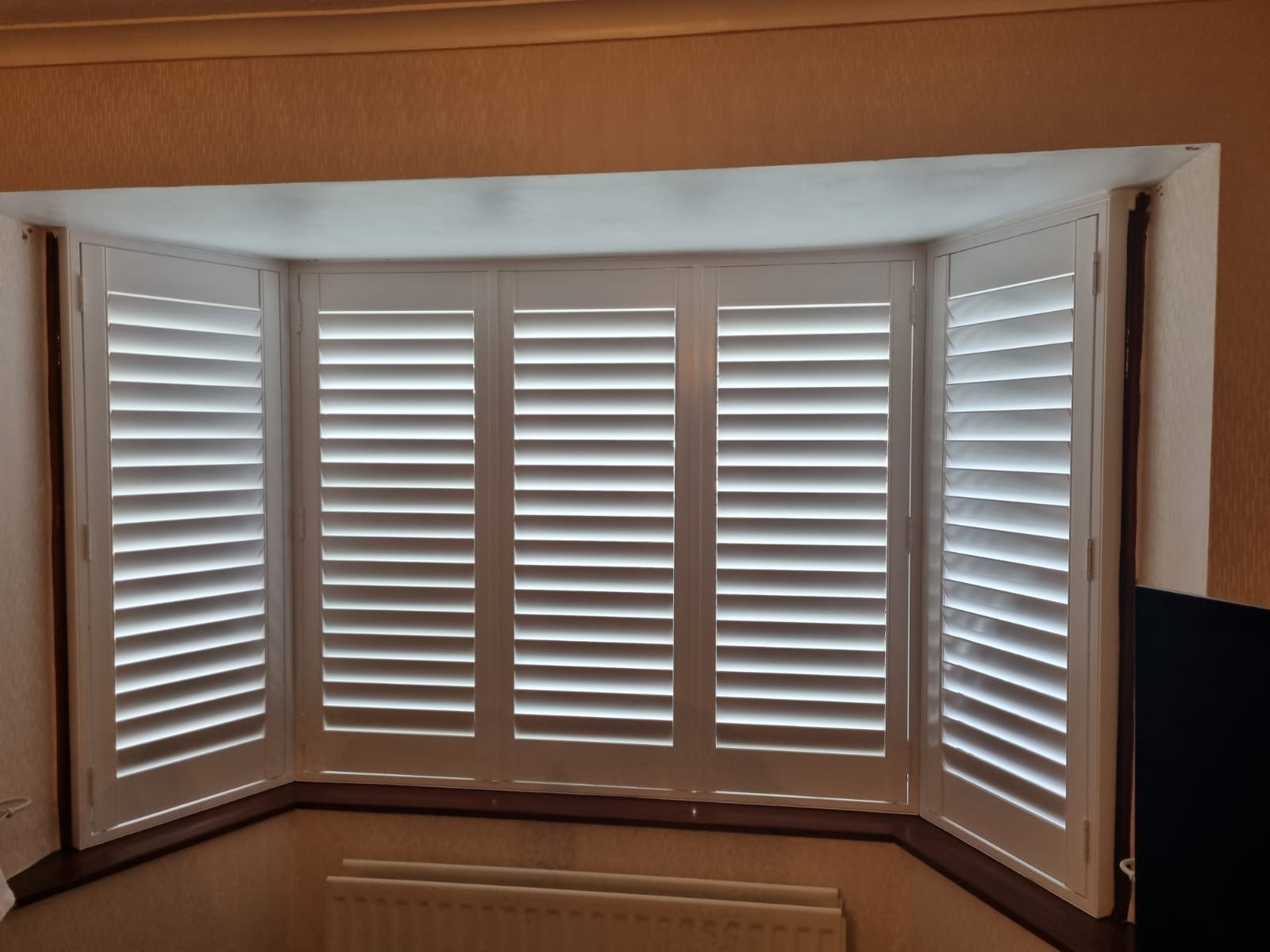 White shutters on a window in a living room.