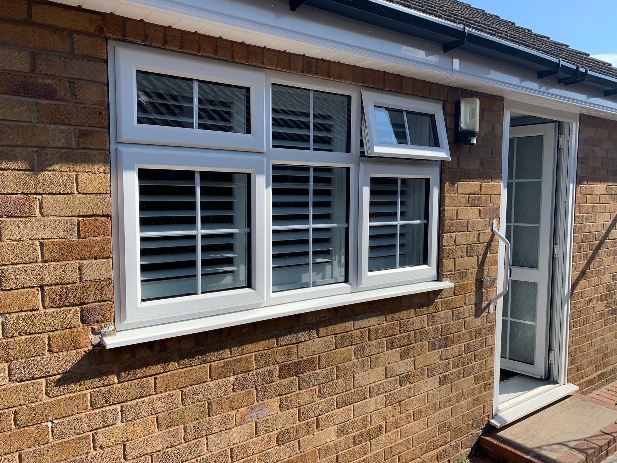 A window in a brick house with white shutters.