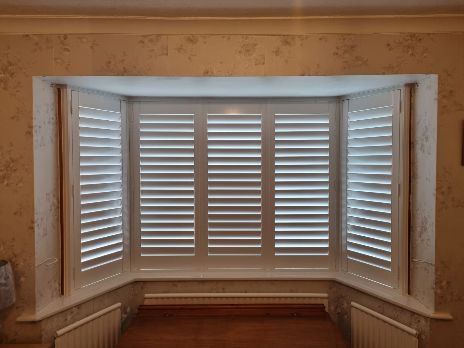 White shutters on a window in a room.