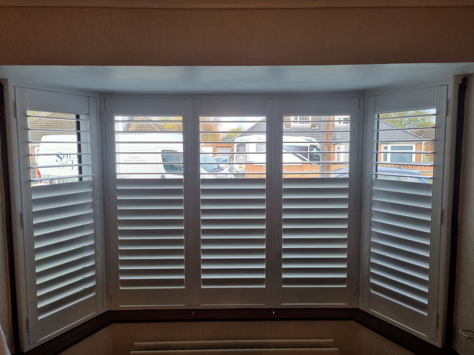 White shutters on a window in a room.