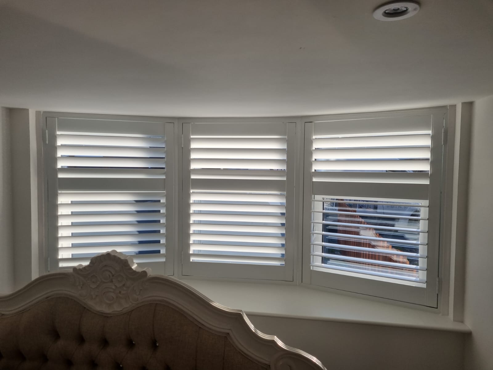 White shutters on a window in a bedroom.