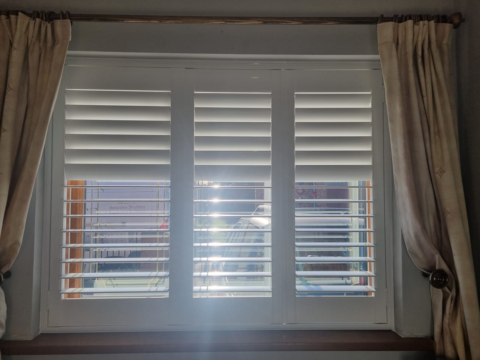 White shutters on a window in a room.