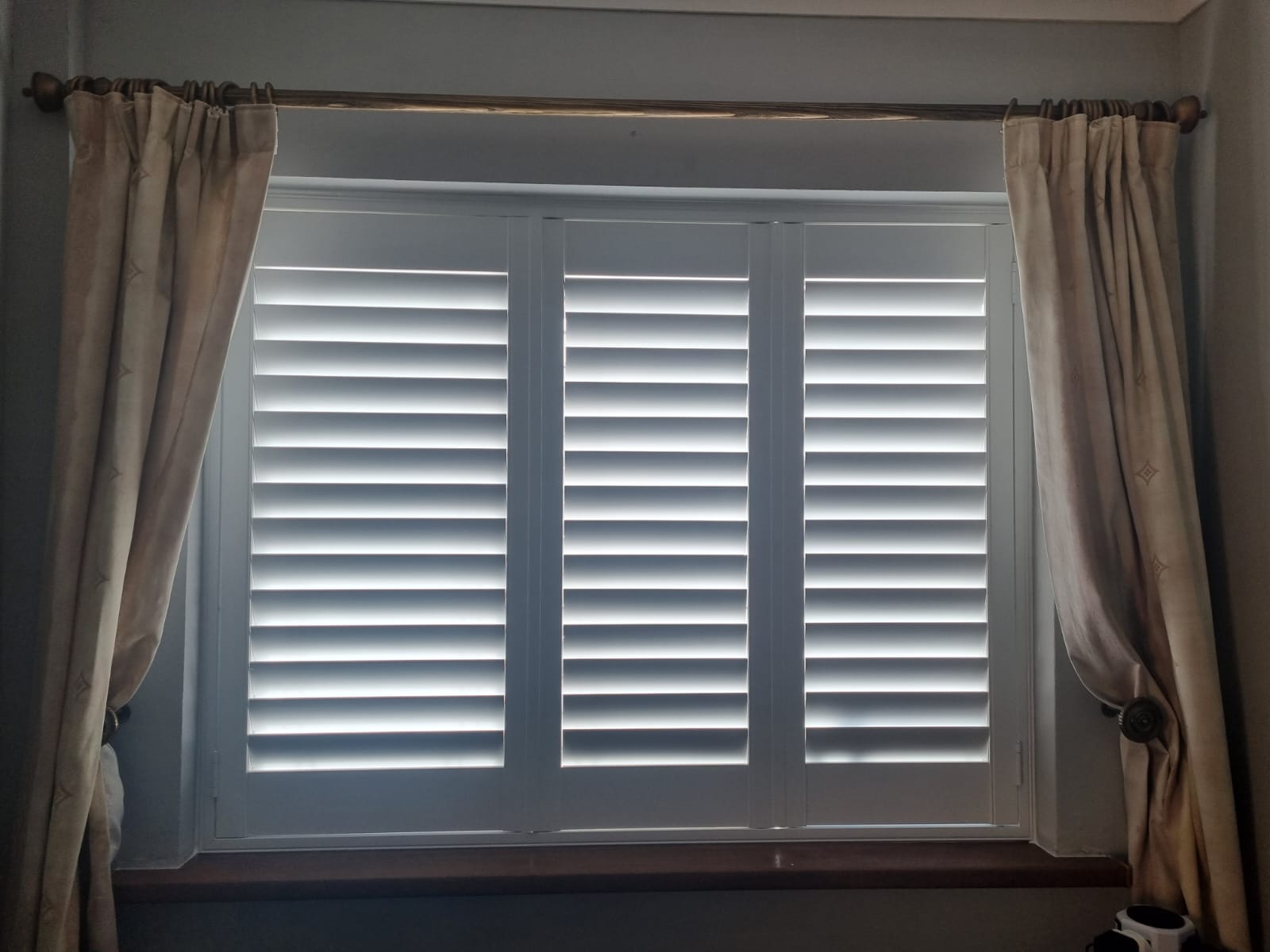 White shutters on a window in a room.
