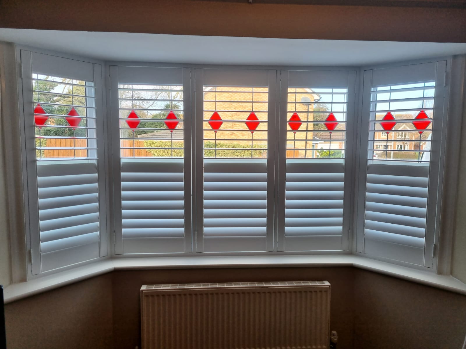 A white window with red shutters and a radiator.