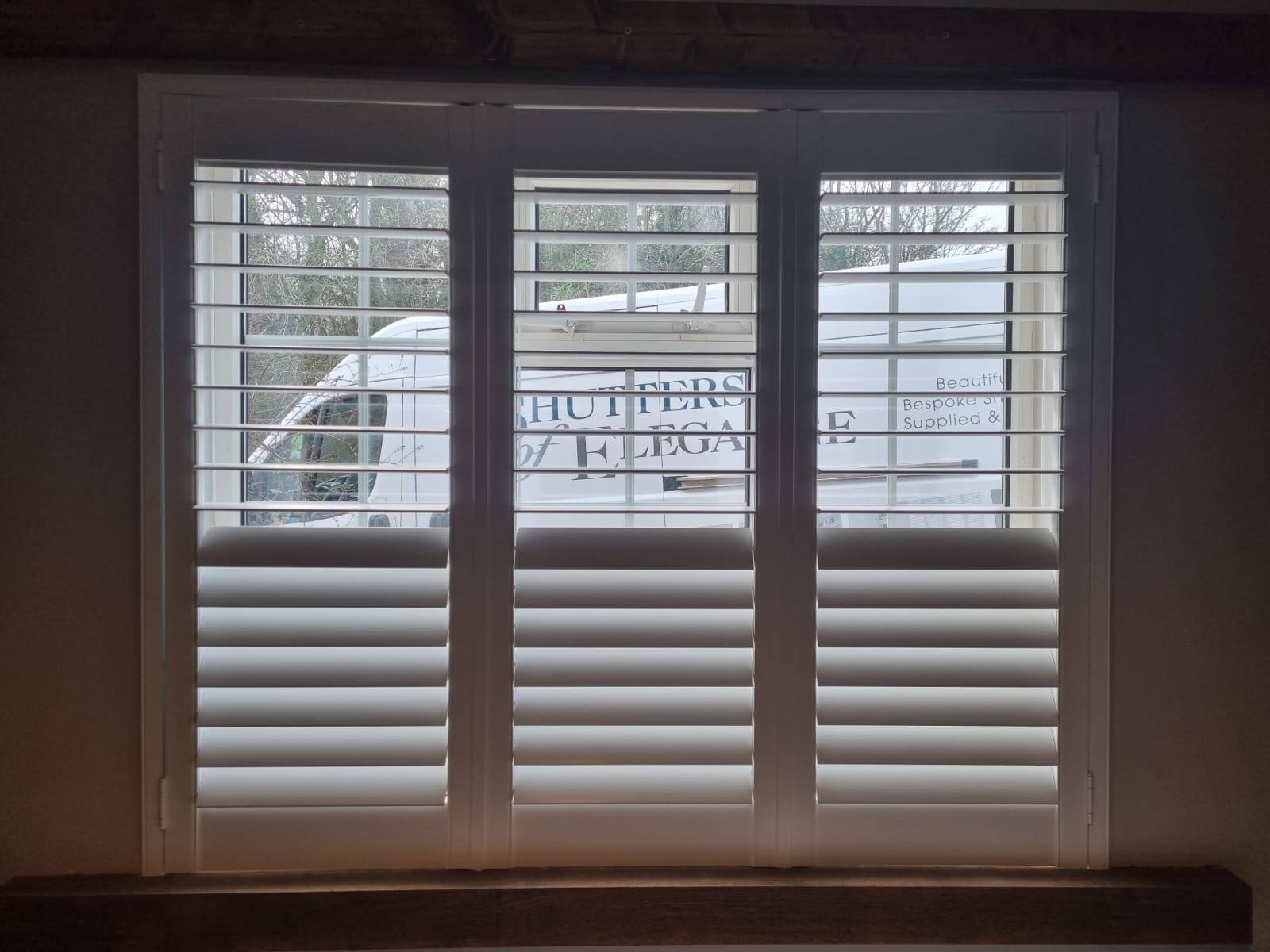White shutters on a window in a room.