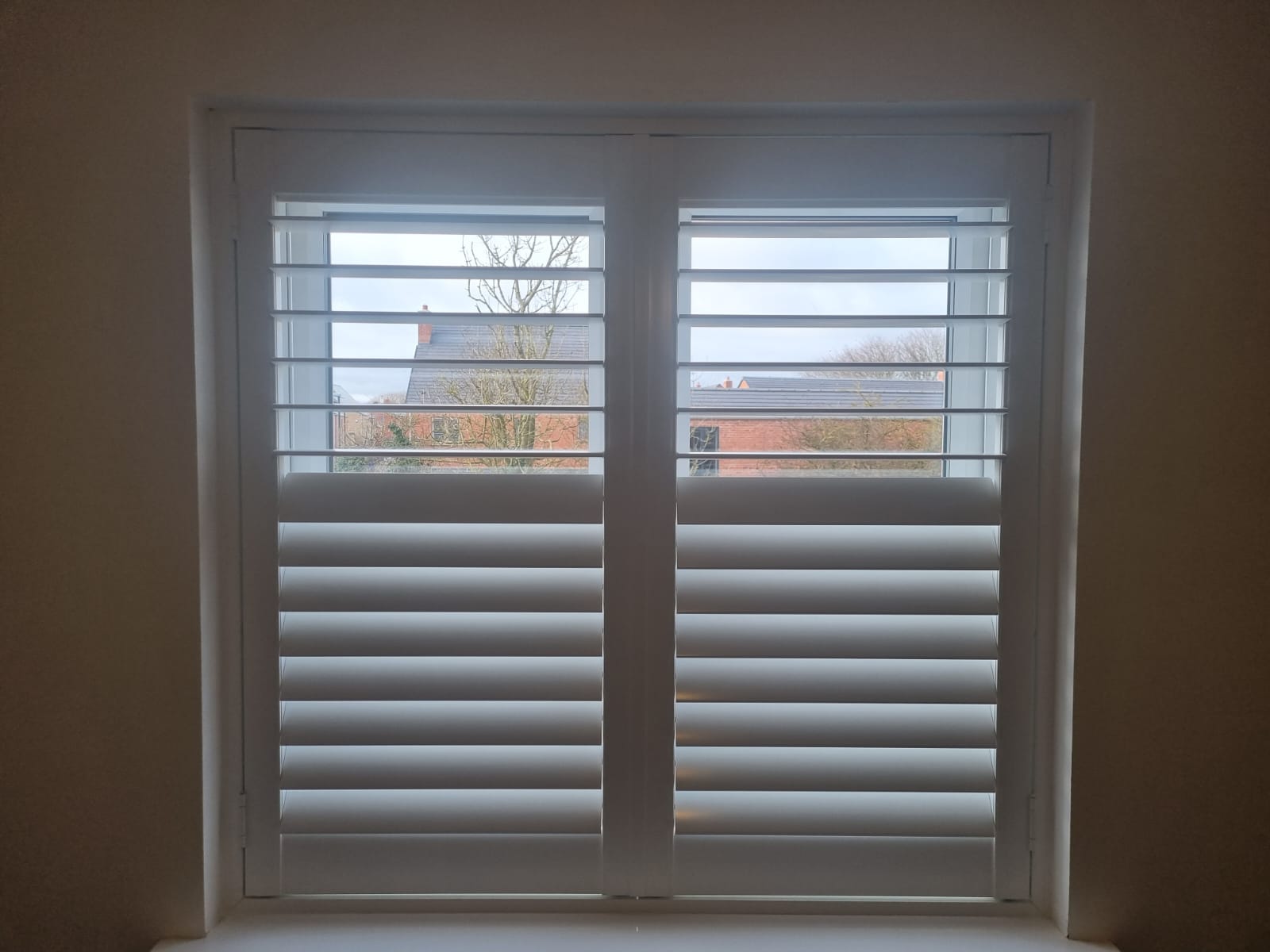 White shutters on a window in a room.