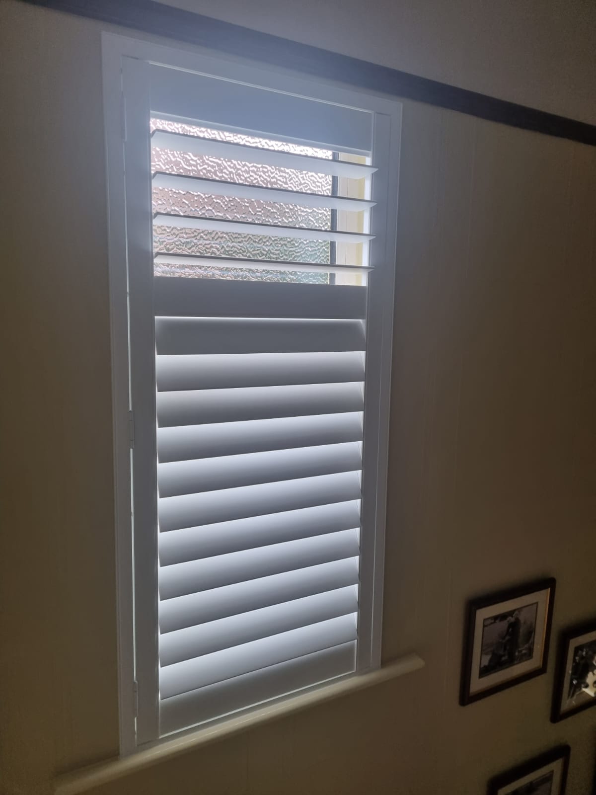 White shutters on a window in a room.