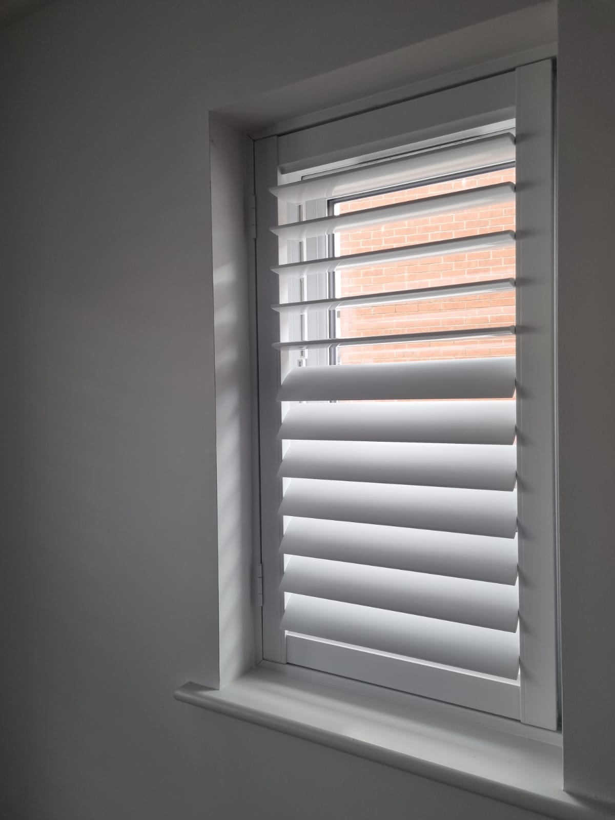 White shutters on a window in a room.