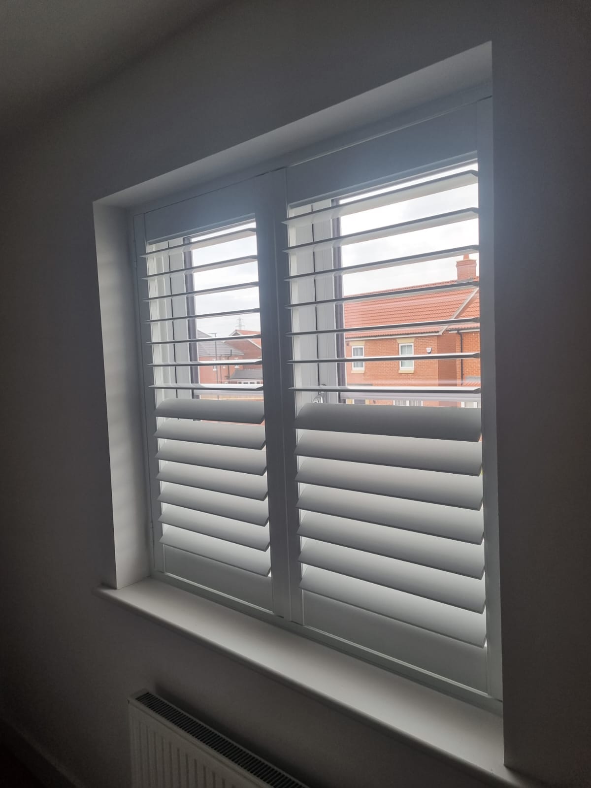 White shutters on a window in a room.