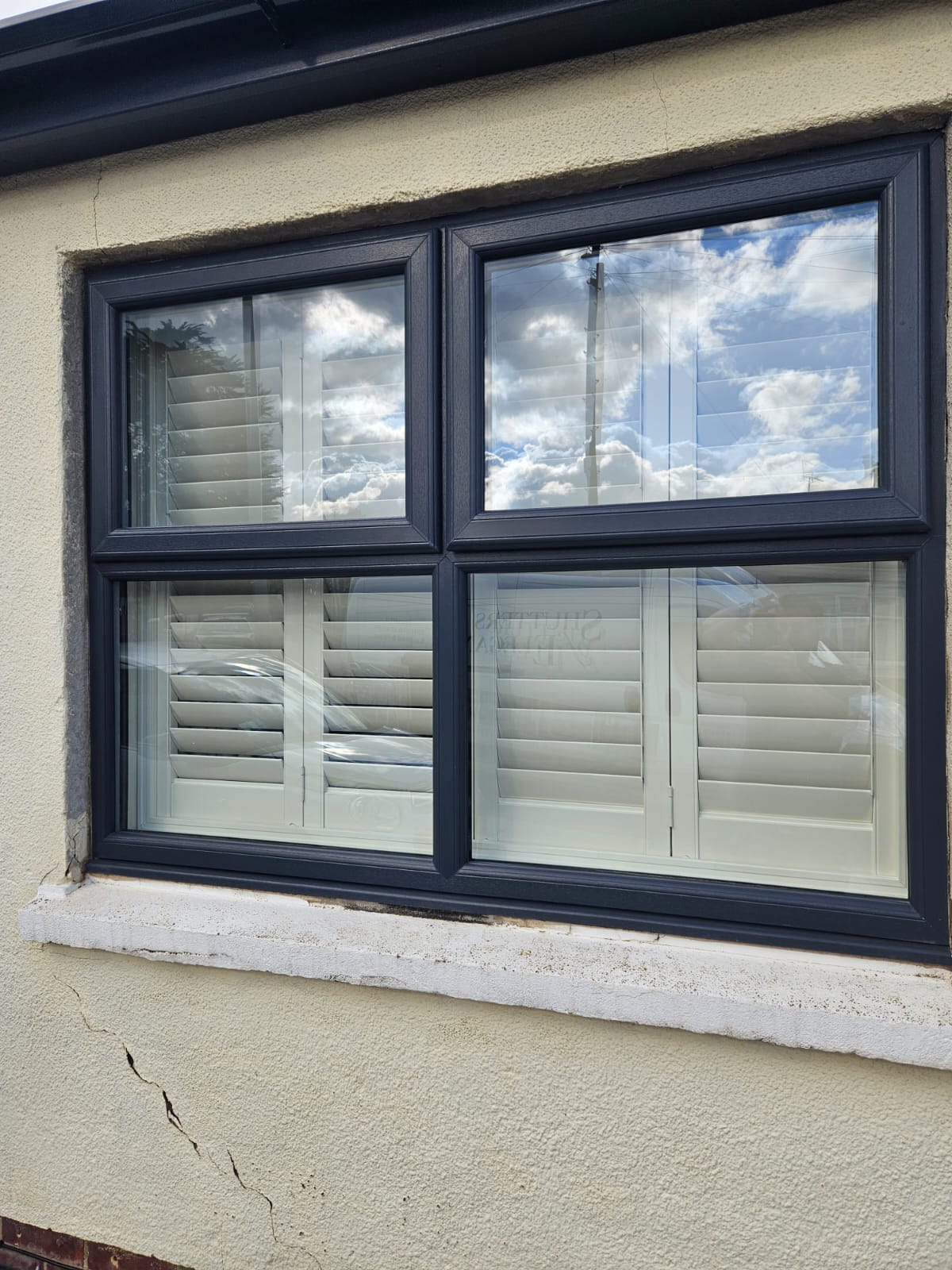 A black window with shutters on it.