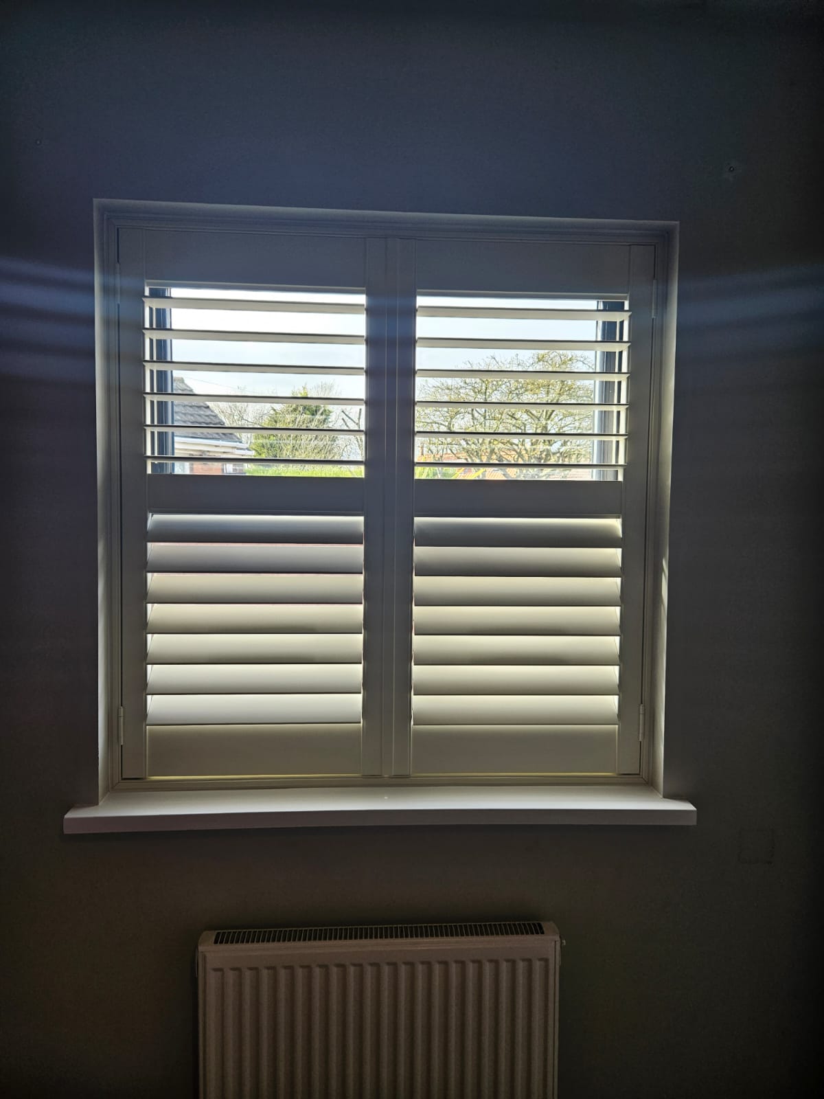 White shutters on a window in a room.