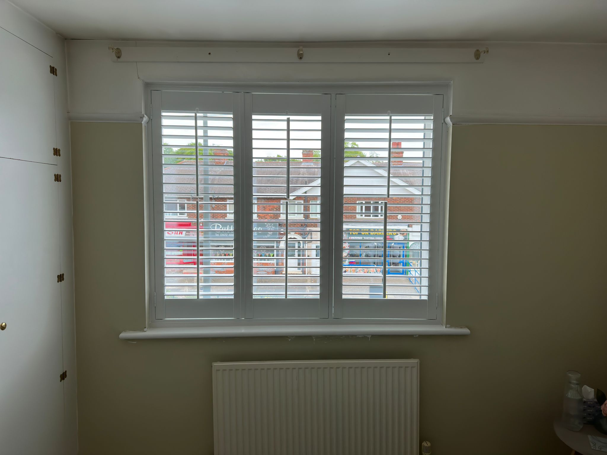 A room with white shutters and a radiator.
